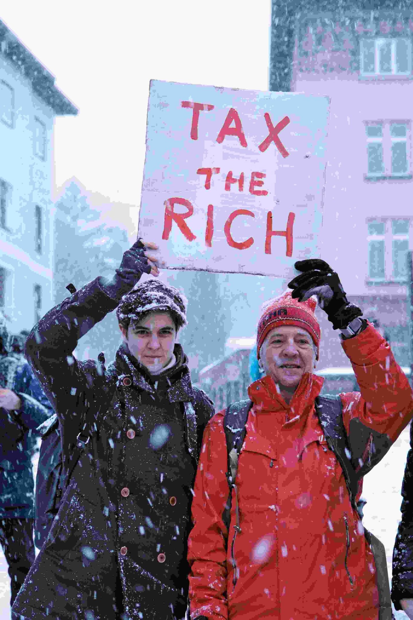 Imagem colorida de milionários protestando pela taxação de grandez riquezas em Davos, na Suíça