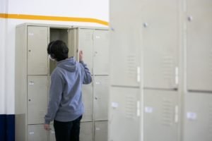 Foto colorida de jovem abrindo seu armário na escola - Metrópoles