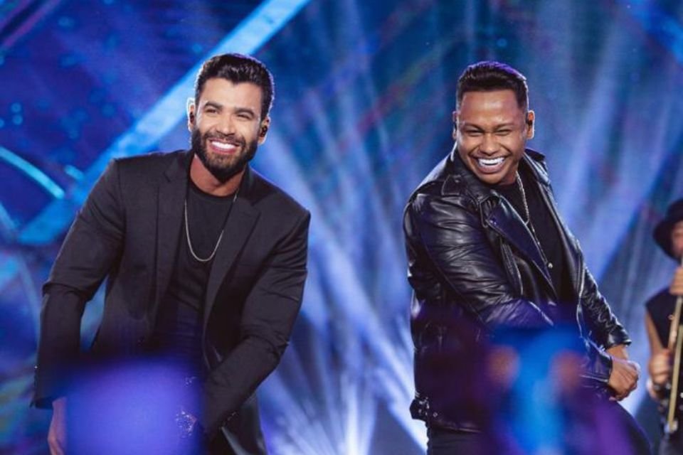A foto colorida mostra os cantores Gusttavo Lima e Junior Marques