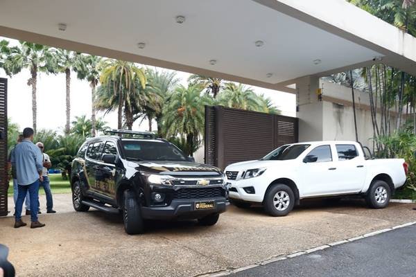 Polícia Federal deixa residência do governador afastado do DF, Ibaneis Rocha, após cerca de 2h30min de buscas. Na imagem, duas viaturas aparecem estacionadas no portão - Metrópoles