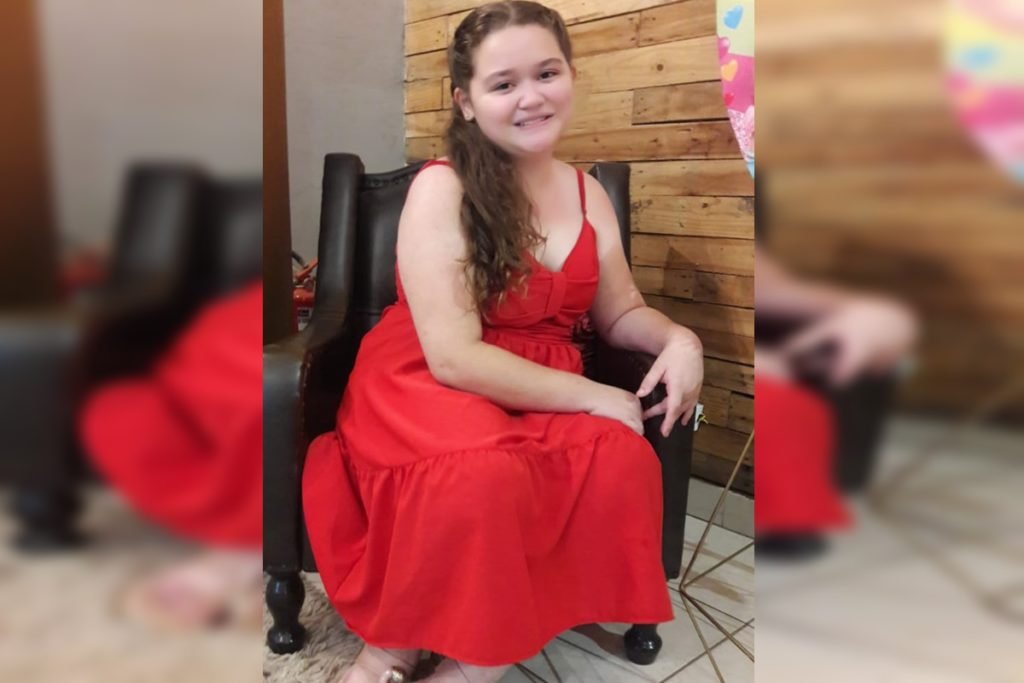 Foto de uma jovem com vestido vermelho sentada em uma poltrona preta