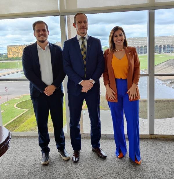 Fotografia colorida mostra dois homens e uma mulher