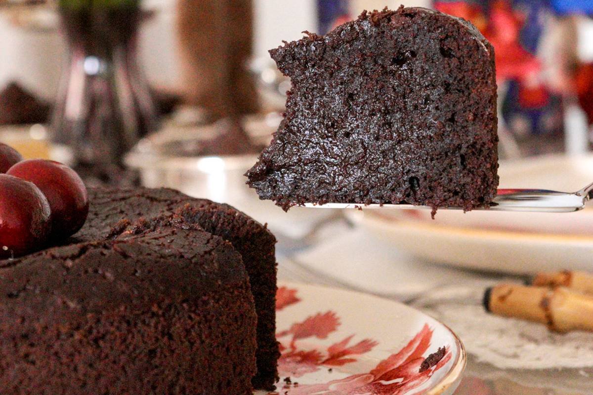 Foto colorida de fatia de bolo de chocolate ao lado de bolo quase inteiro - Metrópoles