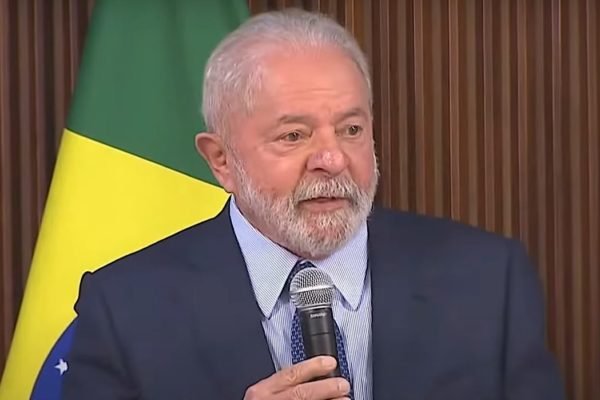Presidente Lula fala a governadores em encontro no Palácio do Planalto. Ele segura microfone, diante de bandeira do Brasil - Metrópoles