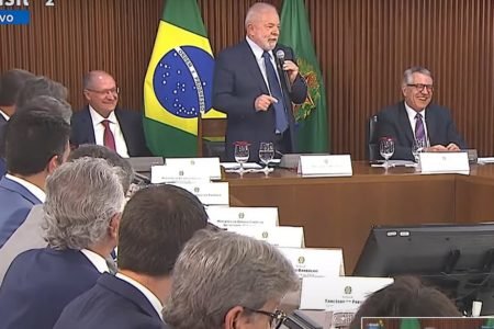 Presidente Lula fala à governadores em encontro no Palácio do Planalto. Ele segura microfone, diante de bandeira do Brasil - Metrópoles