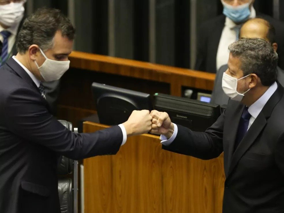 Os presidentes do Senado, Rodrigo Pacheco, e Câmara, Arthur Lira, se cumprimentam no plenário da casa legislativa. Ambos usam máscara e tocam os punhos - Metrópoles