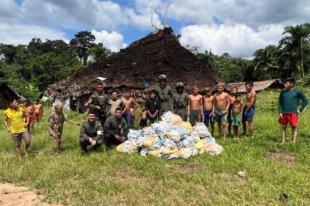 Foto colorida de agentes da FAB após a entrega de cestas básicas no território Yanomami - Metrópoles