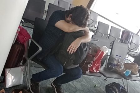 Imagem mostra homem de cabeça baixa em aeroporto. Trata-se do professor brasileiro detido e deportado no México - Metrópoles