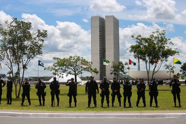 Foto colorida de policiais em pé em frete ao Congresso Nacional