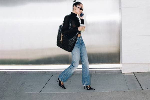 Zoë Kravit ao telefone usando calça jeans, blusa preto, scarpin preto e Icare Bag, da Saint Laurent - Metrópoles