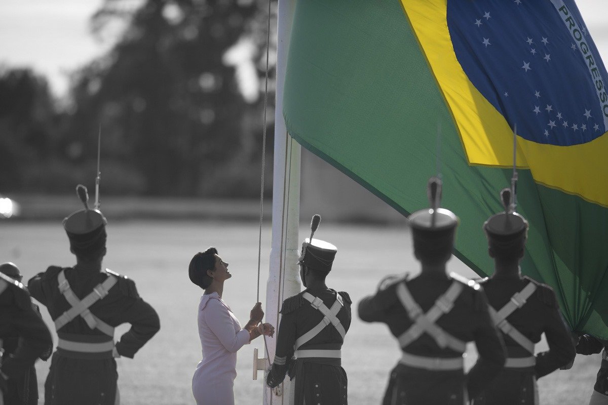 A ex-primeira-dama Michelle Bolsonaro hasteando a bandeira do Brasil em frente ao Palácio do Alvorada, diante de militares. Ela participa de solenidade cívica - Metrópoles