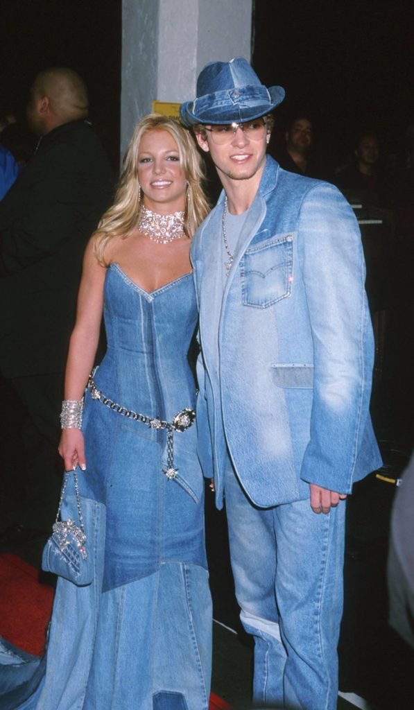 A cantora Britney Spears e o cantor Justin Timberlake na premiação Video Music Awards (VMA) de 2001. Eles dois são brancos, jovens e loiros e usam roupas todas feitas em jeans: ela um vestido longo; ele, uma calça, um blazer e um chapéu. - Metrópoles