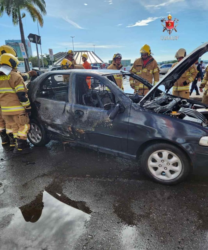 Lateral de Fiat Siena azul com o capô aberto. Carro foi consumido pelas chamas. Foto colorida