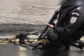 polical segura arma em frente a fuzil no chão