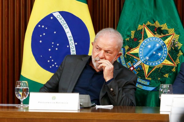 Presidente Lula e governadores se reúnem para discutir ataques antidemocráticos no Palácio do Planalto. Na imagem, o presidente ouve a fala de um governador sentado à mesa, frente a bandeiras do país - Metrópoles