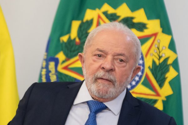 O presidente Lula em reunião com o presidente da Câmara dos Deputados, Arthur Lira e senadores após invasão no Congresso Nacional. Ele aparece em detalhe com bandeira da República atrás - Metrópoles
