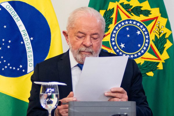 Lula se reúne com Lira e senadores após manifestantes vandalizarem Esplanada dos Ministérios em final de semana. Ele lê documento com bandeiras ao fundo - Metrópoles