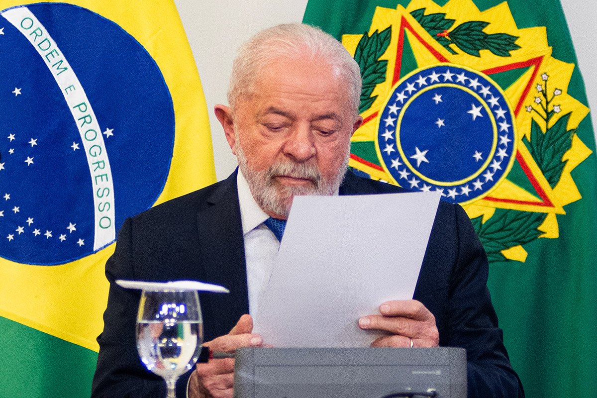 Lula se reúne com Lira e senadores após manifestantes vandalizarem Esplanada dos Ministérios em final de semana. Ele lê documento com bandeiras ao fundo - Metrópoles