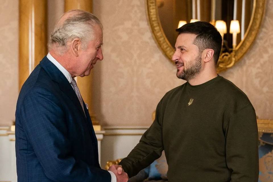 O Rei Charles III cumprimenta o presidente da Ucrânia Volodymir Zelensky com um aperto de mão. Eles sorriem um para o outro em aposento do Palácio de Buckingham - Metrópoles