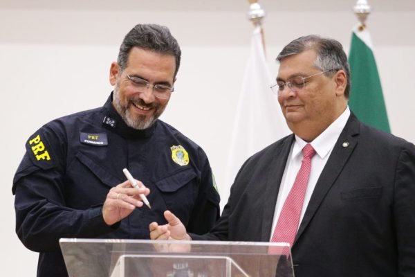 O agente da PRF, Fernando Oliveira, toma posse como novo Diretor-Geral da Polícia Rodoviária Federal, em cerimônia de apresentação da nova Diretoria da instituição. No detalhe, o ministro Flávio Dino assina termo de posse, ambos sorrindo - Metrópoles
