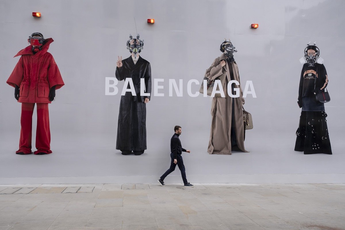 Painel nas ruas de Londres, na Inglaterra, em janeiro de 2022, que divulga as roupas da marca Balenciaga. Um homem branco e jovem anda pela rua, passando em frente ao outdoor. - Metrópoles