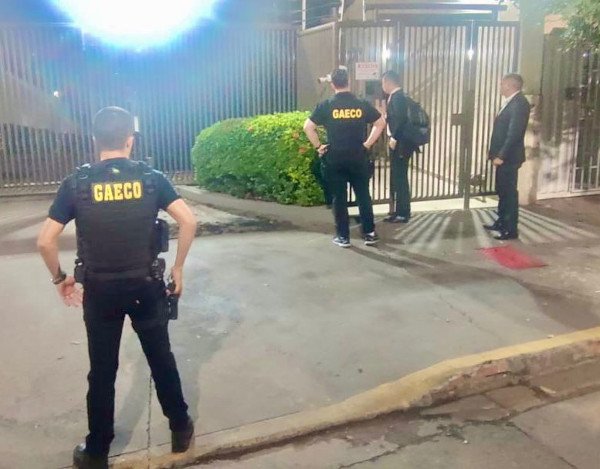 homens vestidos de preto em frente a casa