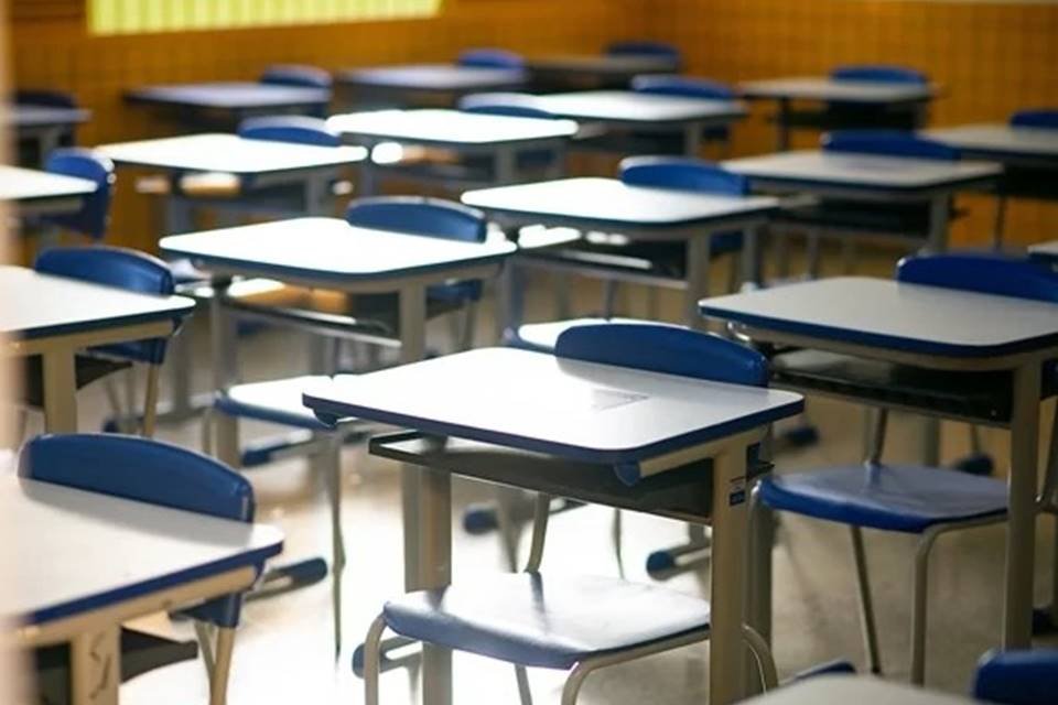 Imagem colorida mostra sala de aula vazia em escola, com carteiras com mesas brancas e cadeiras azuis - Metrópoles