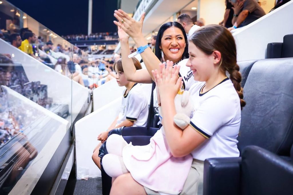 Foto colorida de Simaria e filhos em estádio
