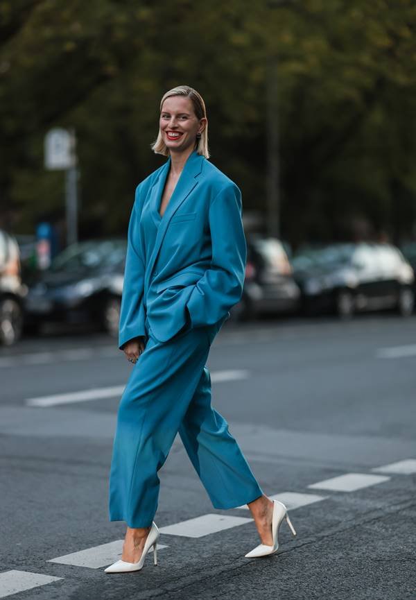 No street style, mulher loira usa conjunto oversized azul de alfaiataria com scarpin branco - Metrópoles