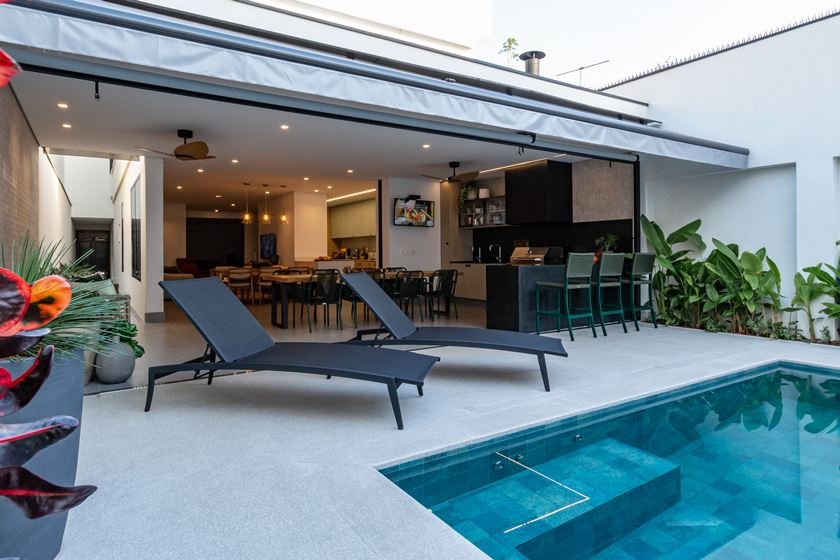 Foto da área externa da casa durante o dia mostrando a piscina