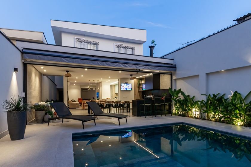 Foto da área externa da casa durante a noite mostrando a piscina