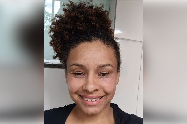 mulhe negra com cabelo preso sorri em selfie