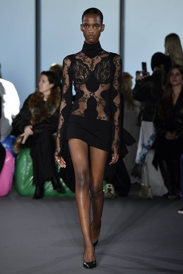 Na passarela, modelo usa look com minissaia preta de renda manga longa e gola alta - Zig Proxy