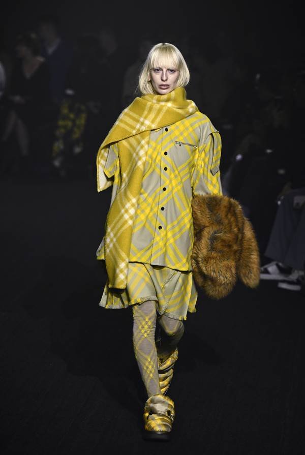 Na passarela, modelo usa look xadrez amarelo com lenço no pescoço - Zig Proxy