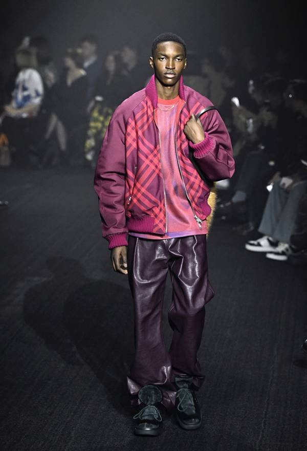 Na passarela, modelo usa calça de couro escura com jaqueta bomber xadrez rosa - Zig Proxy