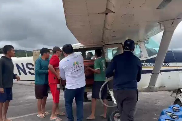 Caixões sendo tirados do avião por indígenas em Surucucu — Foto: Divulgação/Condisi-YY