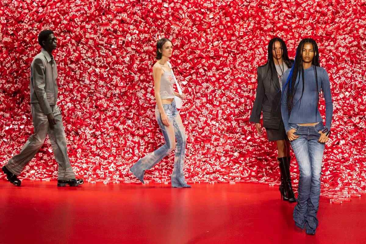 Modelos desfilam com fundo vermelho de camisinhas empilhadas - Metrópoles