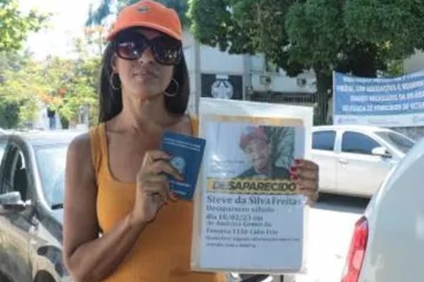 Mãe de ex-jogador encontrado morto em Cabo Frio (RJ) segura cartaz com a foto do filho - Metrópoles