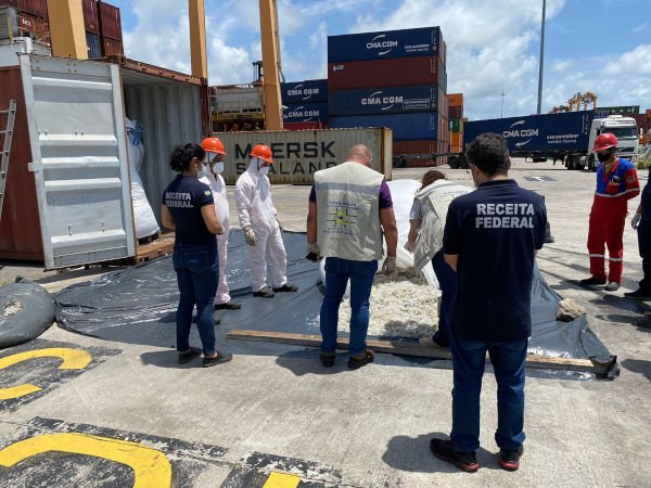 homens com uniformes da receita federal inspecionam objetos no chão