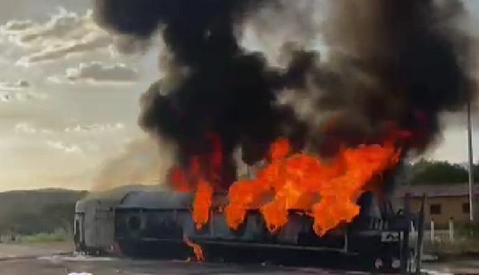 Imagem colorida mostra caminhão-tanque tombado e tomado por fogo