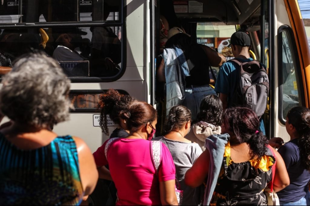 Passageiros entrem em ônibus lotado