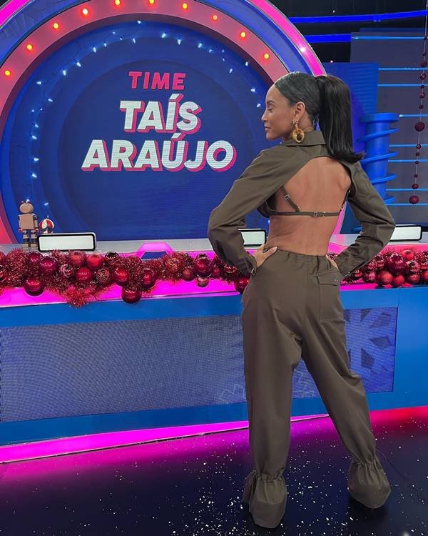 Atriz Taís Araújo de costas usa calça de alfaiataria verde musgo, blazer curto e sutiã da mesma tonalidade. Ela usa o cabelo preso em um rabo de cavalo alto - Metrópoles 