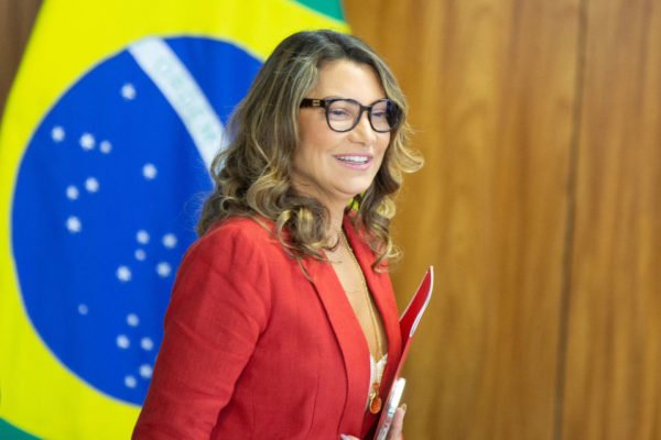 Foto colorida de mulher com terno vermelho e bandeira do brasil - Metrópoles - Janja