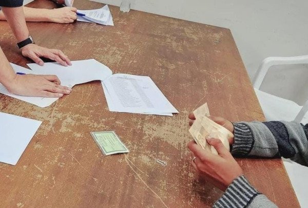 mãos apoiadas na mesa seguram cédulas de dinheiro