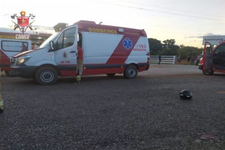 Ambulância estacionada e capacete de moto deixado em cima do asfalto na via 001