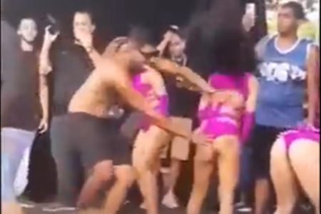 Imagem mostra o momento em que um homem invade o palco de um show e assedia três bailarinas - Metrópoles