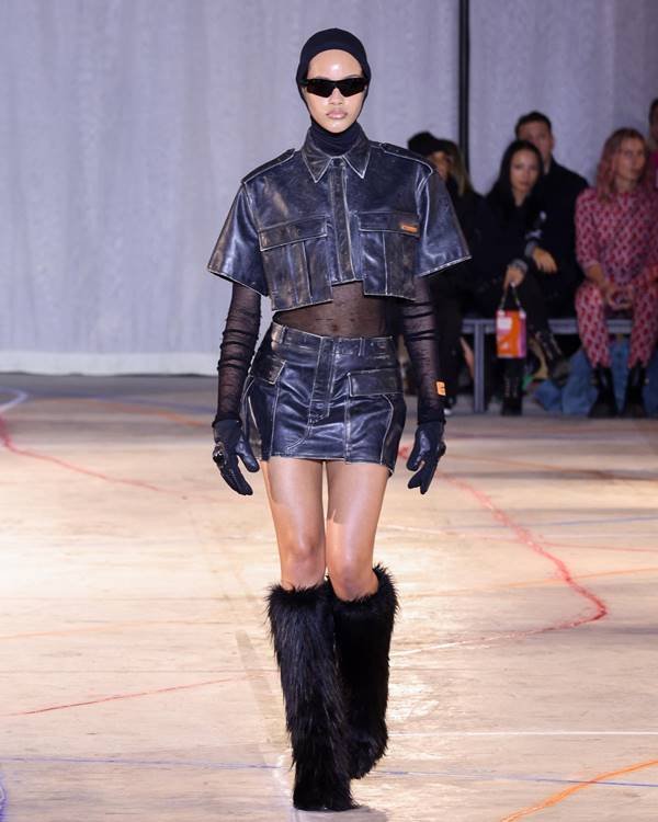 Modelo usa jaqueta pequena de couro, saia de couro, óculos escuros e botas de pelinhos - Metrópoles 