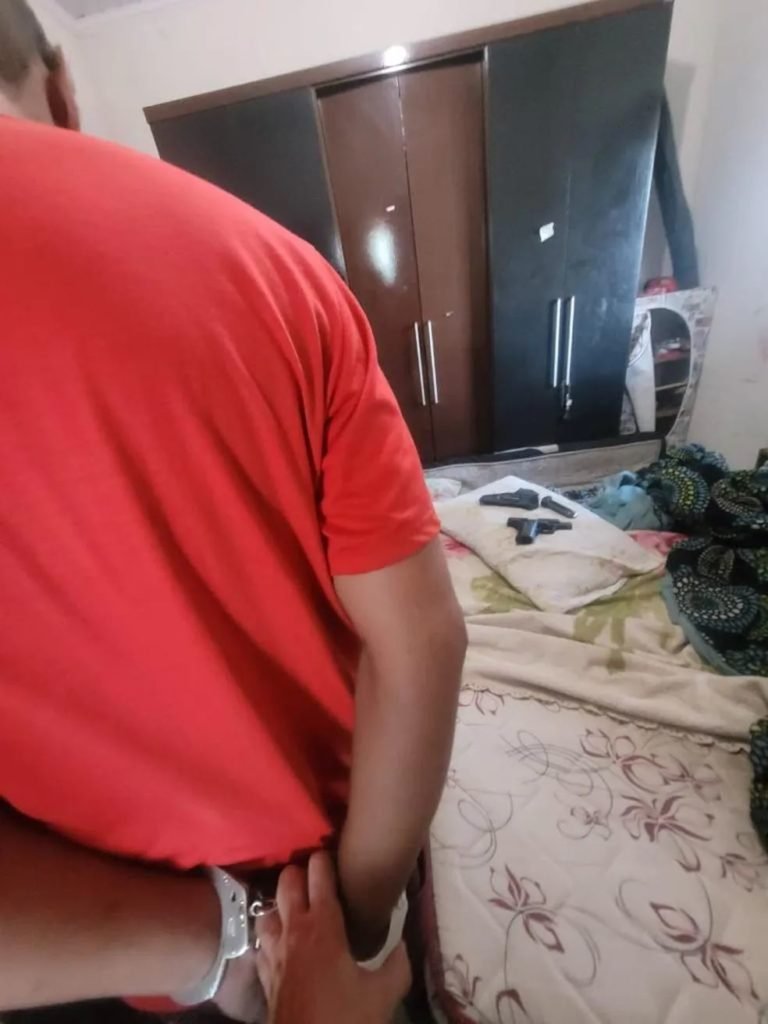 Foto colorida de um homem negro de costas com as mãos algemadas - Metrópoles