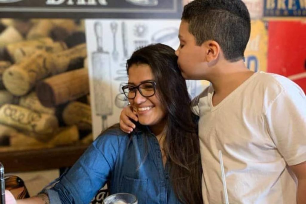 mulher posa sorrindo com criança beijando a cabeça dela - metrópole