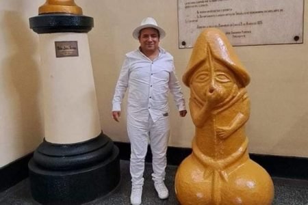 homem ao lado de estátua de pênis - metrópoles